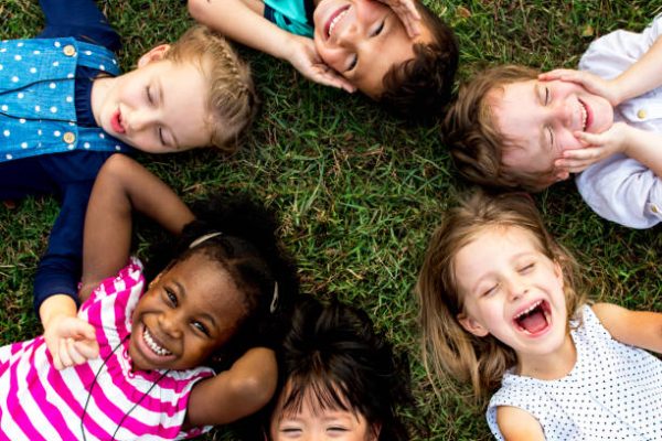 Group of kindergarten kids lying on the grass at park and relax with smiling Group of kindergarten kids lying on the grass at park and relax with smiling